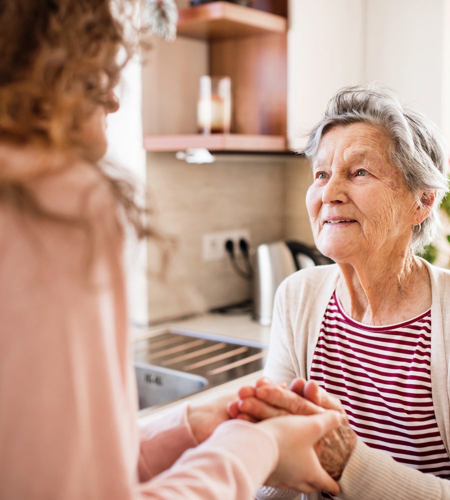 Betreuerin hält die Hand einer Seniorin zu Hause